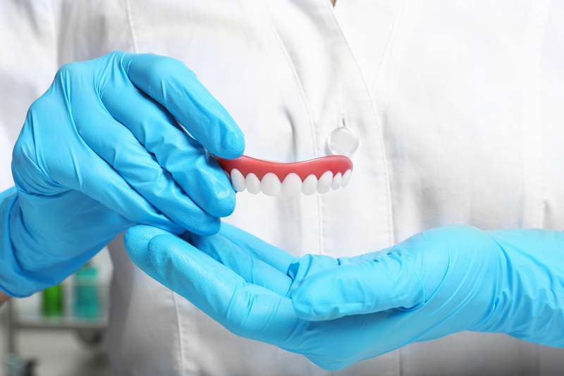 Photo of a doctor holding a pair of implant dentures.