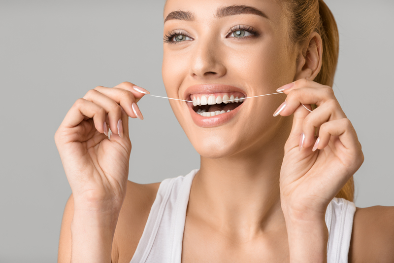 Close up photo of a woman flossing her teeth.