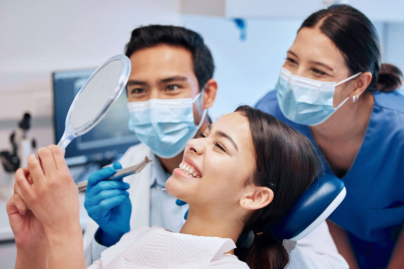 patient looking in mirror as dentist admire they're work