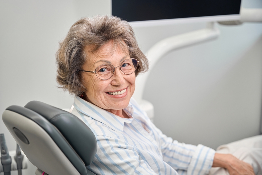 Close-up of a dentist applying a thin porcelain dental veneer to a patient's tooth, showcasing the precision and artistry involved in cosmetic dentistry. The image focuses on the hands of the dentist and the detailed application process, highlighting the natural look and feel of the veneer. No text on image.