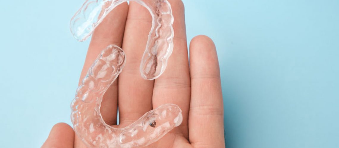 a dental patient hand holding clear aligners.
