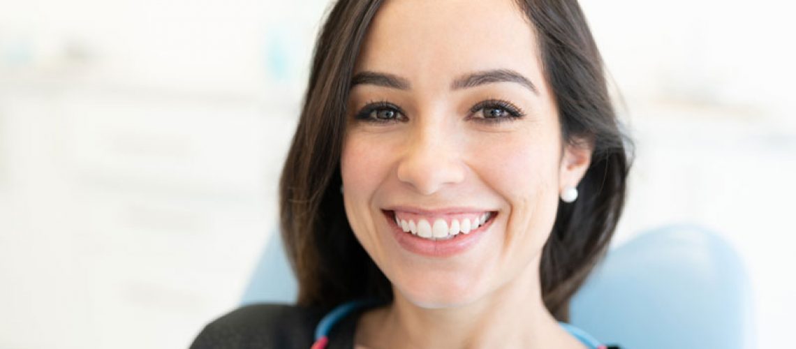 a full mouth dental implant patient smiling in a chair.