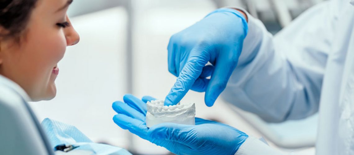 a dentist showing an implant patient a dental implant model.