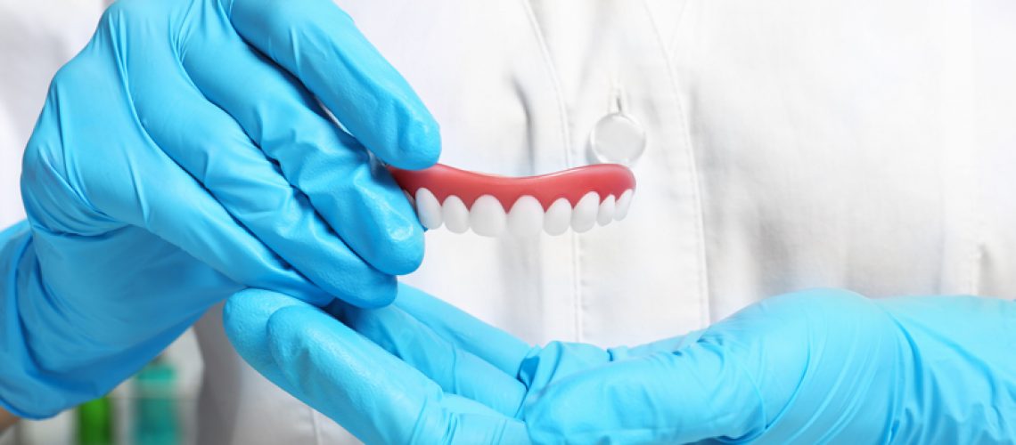 Photo of a doctor holding a pair of implant dentures.