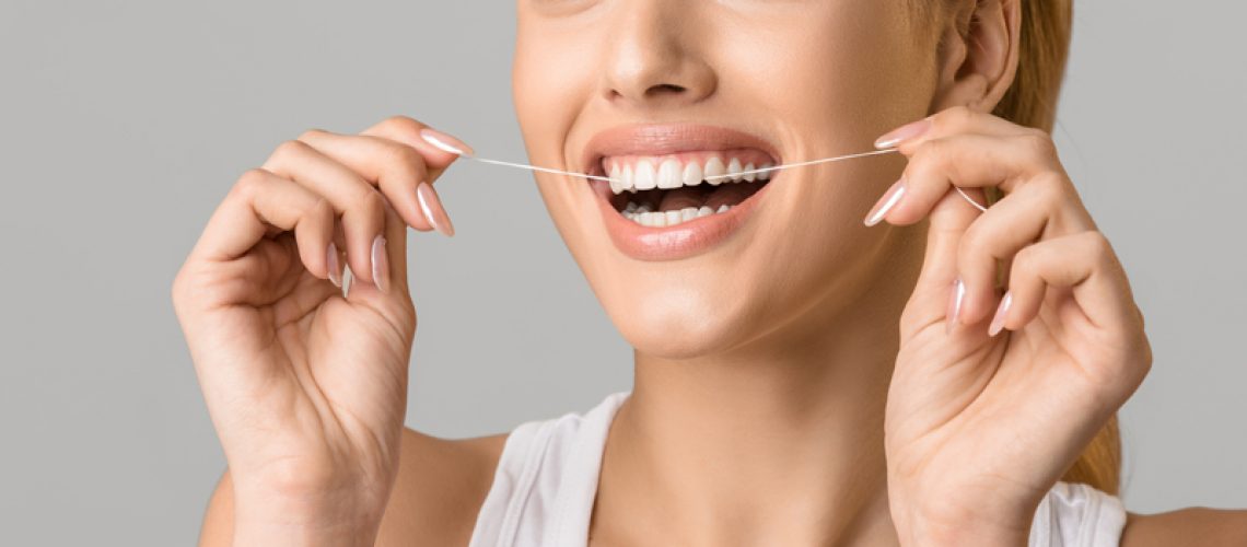 Close up photo of a woman flossing her teeth.
