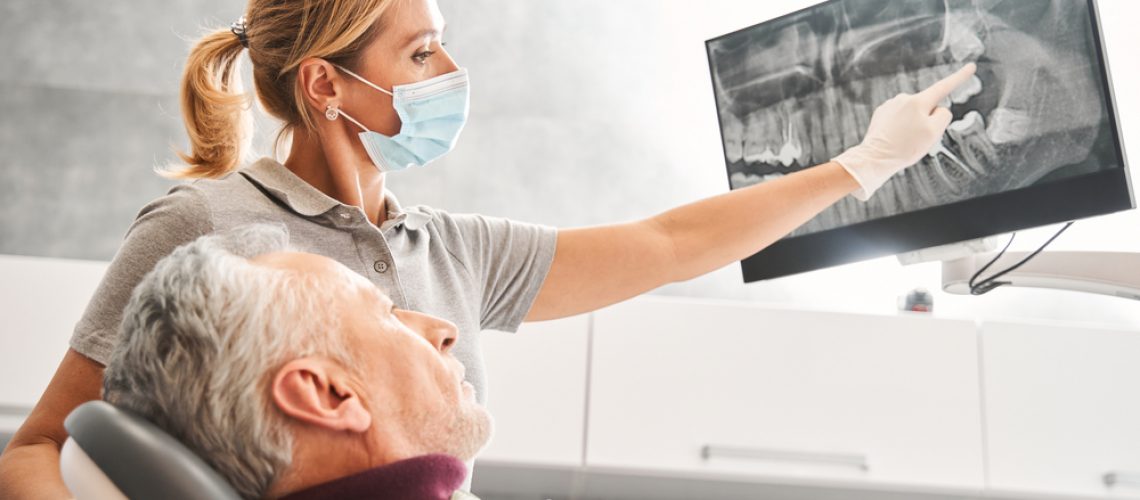 Close-up photo of a dentist placing a tooth implant into a patient's jaw, showcasing the precision and care involved in the procedure. No text on the image.
